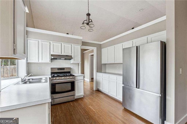 kitchen featuring hanging light fixtures, stainless steel appliances, light countertops, under cabinet range hood, and white cabinetry