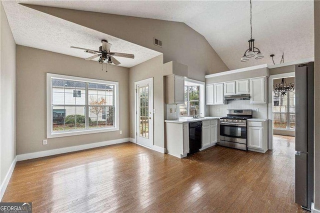 kitchen with pendant lighting, stainless steel appliances, light countertops, white cabinets, and under cabinet range hood