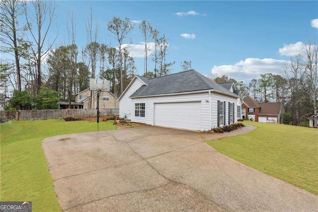 view of side of property featuring driveway, a lawn, an attached garage, and fence