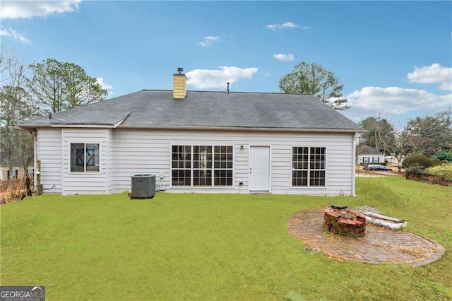 rear view of house featuring a yard, a chimney, central AC, a patio area, and a fire pit