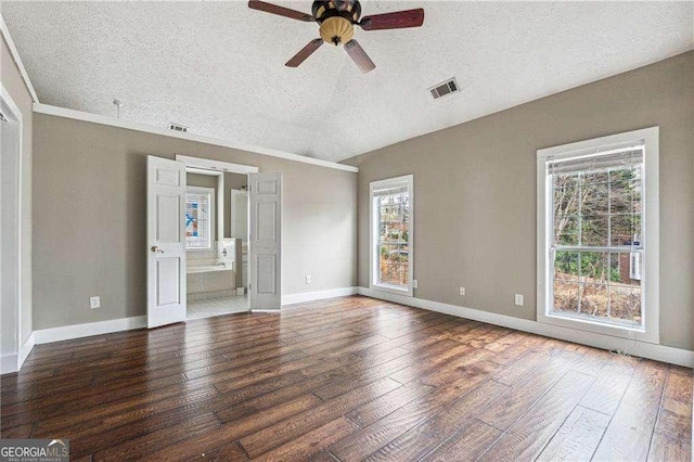 empty room featuring dark wood-style floors, visible vents, a textured ceiling, and baseboards