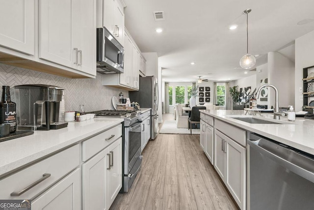 kitchen featuring appliances with stainless steel finishes, pendant lighting, light countertops, and white cabinetry