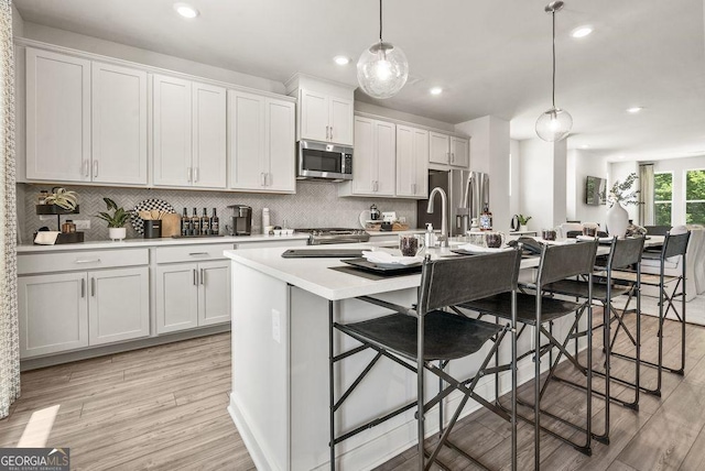 kitchen with a breakfast bar area, pendant lighting, stainless steel appliances, and light countertops