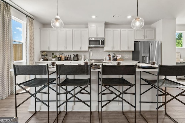 kitchen featuring a kitchen breakfast bar, stainless steel appliances, and pendant lighting