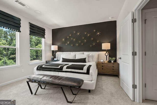 bedroom featuring baseboards, an accent wall, visible vents, and light colored carpet