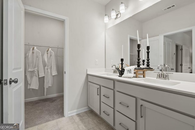 full bath with a walk in closet, visible vents, a sink, and double vanity