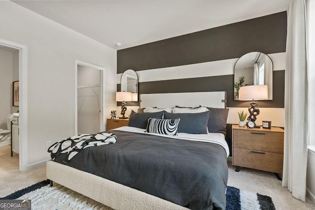 bedroom with light carpet, baseboards, and a walk in closet