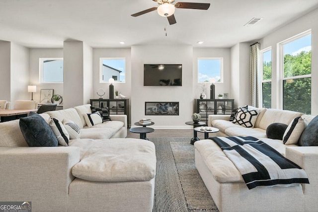 living area with a glass covered fireplace, visible vents, recessed lighting, and wood finished floors