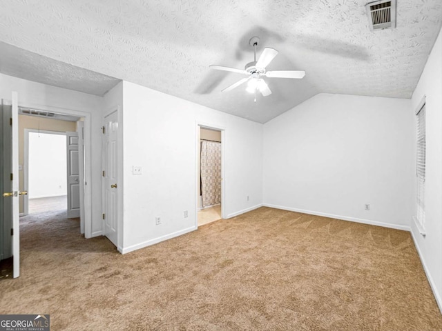 unfurnished bedroom with baseboards, visible vents, vaulted ceiling, a textured ceiling, and carpet floors