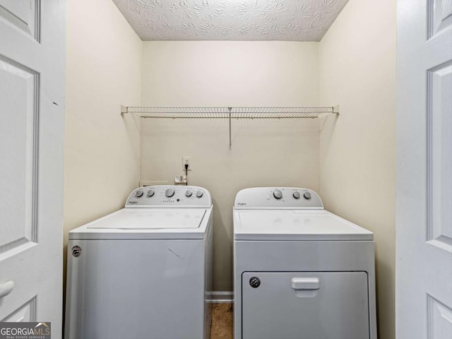 washroom with a textured ceiling, laundry area, and washer and clothes dryer