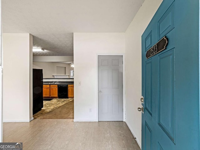 foyer entrance featuring a textured ceiling, baseboards, and wood finished floors