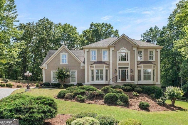 colonial house featuring a front lawn and stucco siding