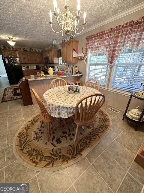 dining space with crown molding, light tile patterned floors, visible vents, a textured ceiling, and a chandelier