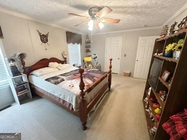 bedroom with visible vents, light colored carpet, ornamental molding, ceiling fan, and a textured ceiling