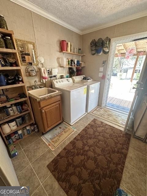 washroom featuring light tile patterned floors, a sink, independent washer and dryer, cabinet space, and crown molding