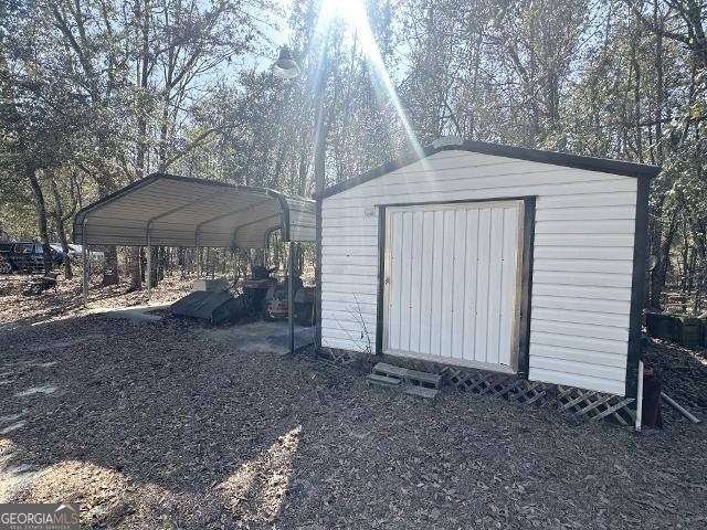 view of shed with a carport and driveway