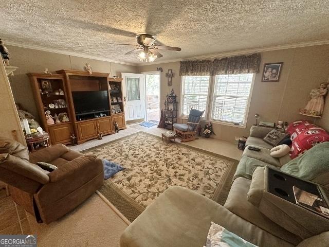 living room with a textured ceiling, a ceiling fan, crown molding, and carpet flooring