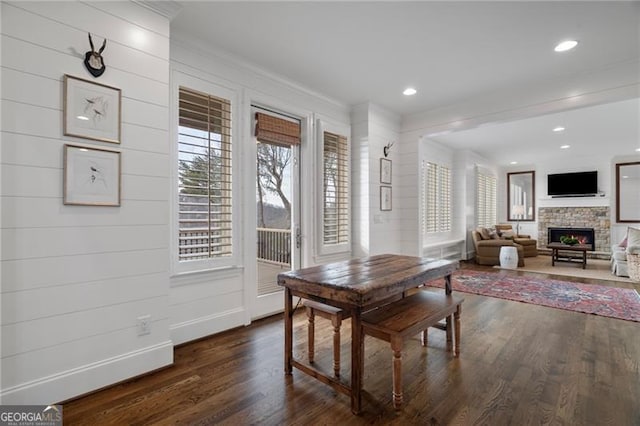 dining room featuring recessed lighting, dark wood-type flooring, a fireplace, baseboards, and ornamental molding