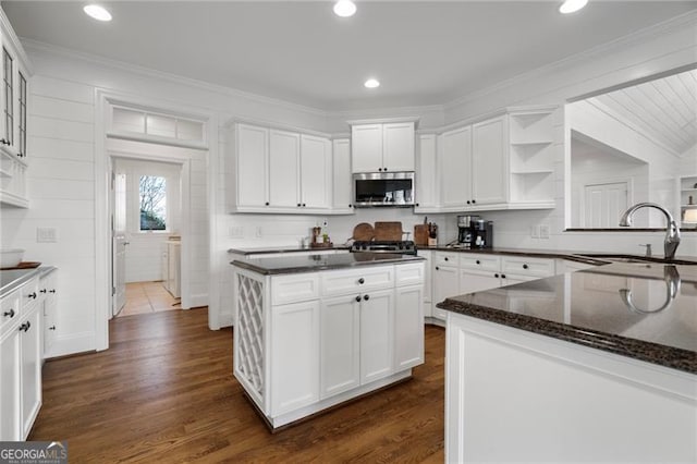 kitchen with stainless steel microwave, white cabinets, a sink, and a center island