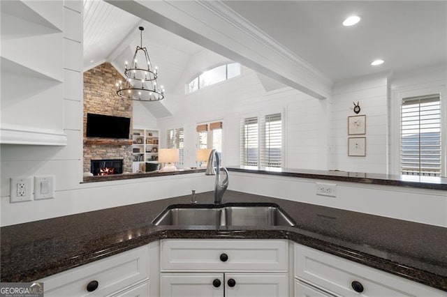 kitchen with dark stone countertops, a sink, white cabinetry, and pendant lighting