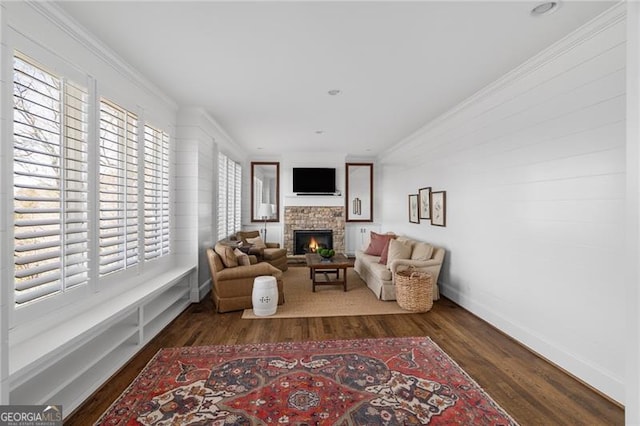 living room featuring baseboards, a fireplace, ornamental molding, and dark wood-style flooring