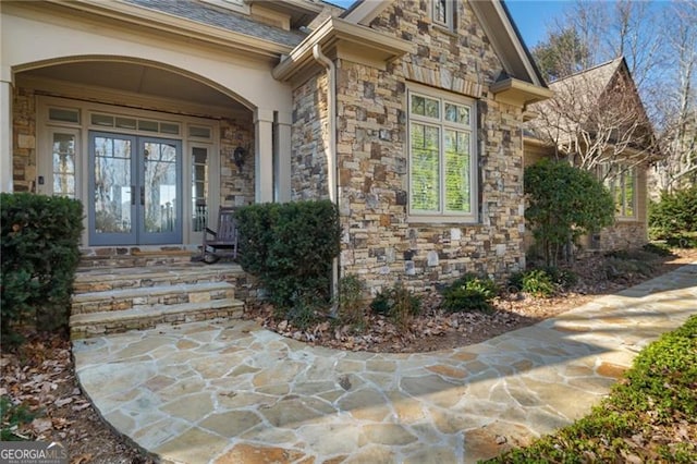 property entrance featuring stone siding, roof with shingles, and french doors