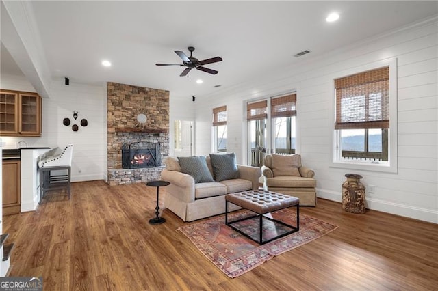 living room with dark wood-style flooring, a fireplace, recessed lighting, visible vents, and baseboards