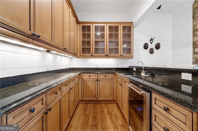 kitchen with light wood-style flooring, wine cooler, glass insert cabinets, dark stone countertops, and crown molding