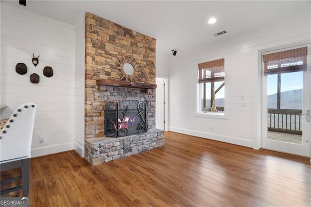 unfurnished living room featuring a mountain view, a fireplace, wood finished floors, visible vents, and baseboards