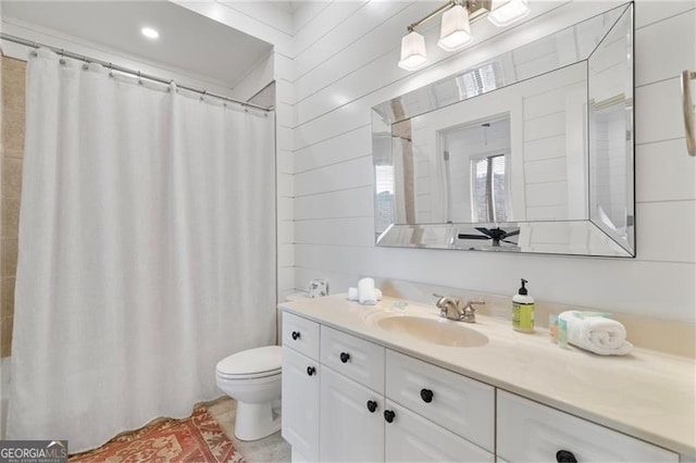 full bath with toilet, vanity, and wooden walls