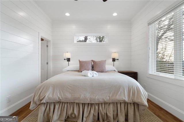 bedroom featuring multiple windows, baseboards, and wood finished floors