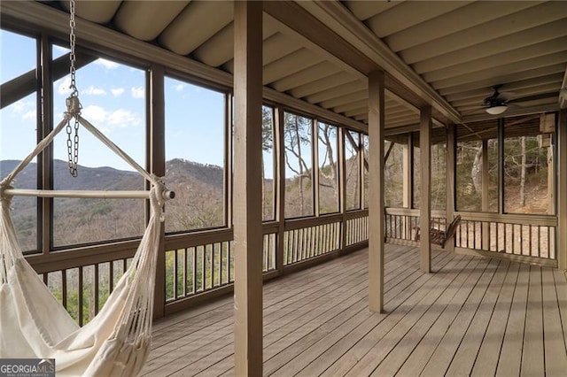 unfurnished sunroom featuring a mountain view and a ceiling fan