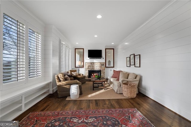 sitting room with a healthy amount of sunlight, dark wood-type flooring, and a stone fireplace