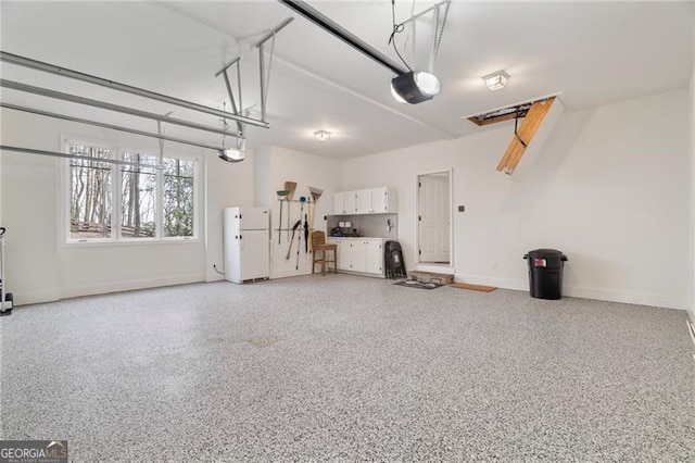 garage with freestanding refrigerator, baseboards, and a garage door opener