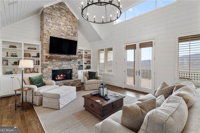 living area with built in features, wood finished floors, vaulted ceiling, french doors, and a fireplace