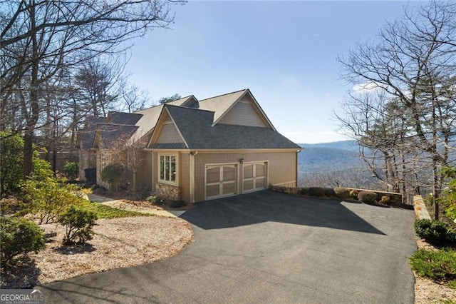 view of home's exterior featuring a garage, stone siding, driveway, and a mountain view