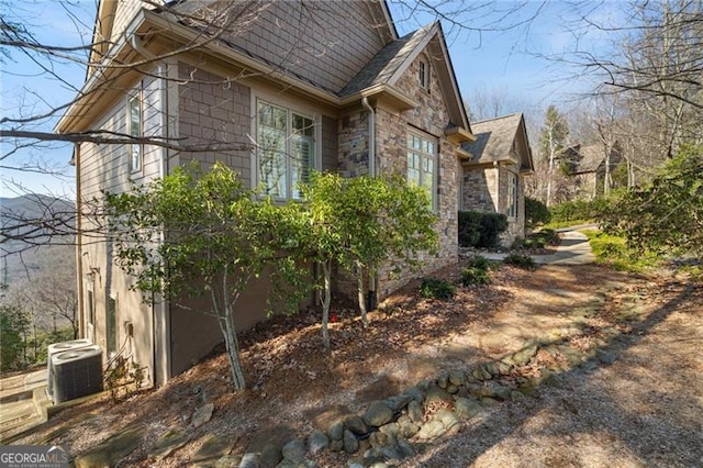 view of property exterior with stone siding and cooling unit