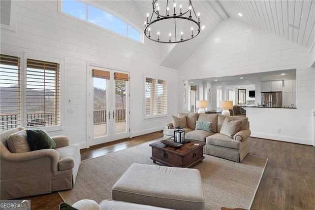 living area featuring an inviting chandelier, high vaulted ceiling, dark wood-type flooring, and french doors