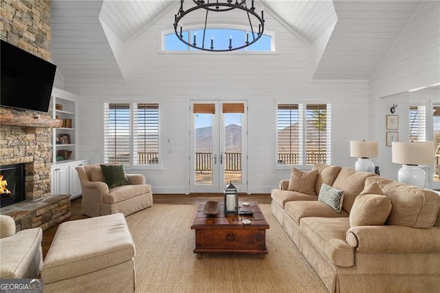 living area with lofted ceiling, light wood-style flooring, french doors, a fireplace, and a notable chandelier