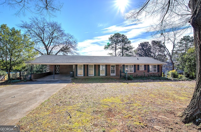 single story home featuring a carport, brick siding, and driveway