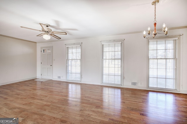 spare room featuring baseboards, visible vents, wood finished floors, crown molding, and ceiling fan with notable chandelier