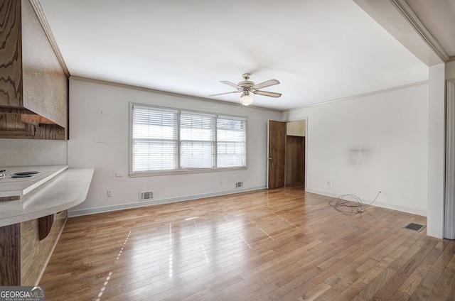 unfurnished living room featuring light wood-style flooring, a ceiling fan, visible vents, and crown molding