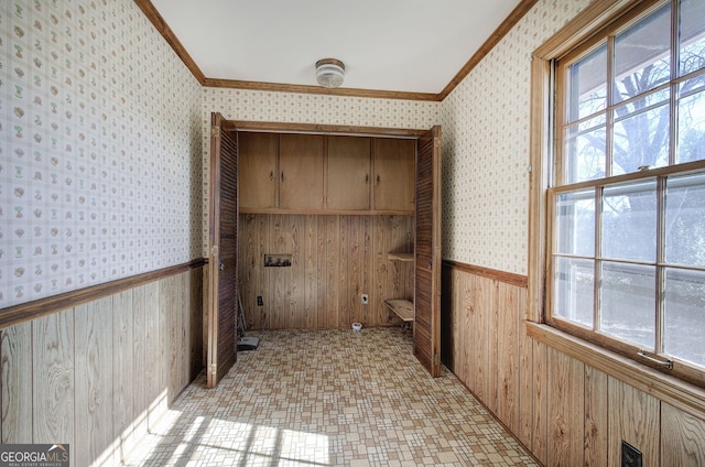 clothes washing area with wallpapered walls, ornamental molding, and wainscoting