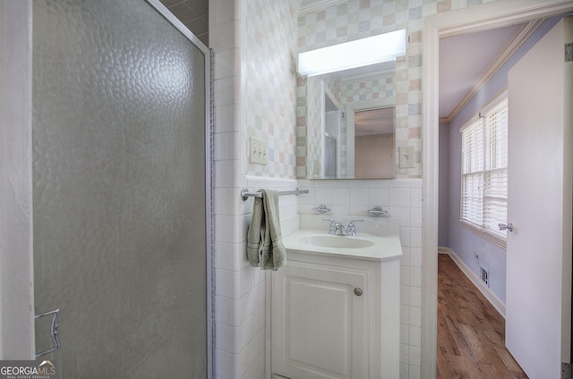 full bathroom featuring wood finished floors, vanity, baseboards, a shower stall, and crown molding