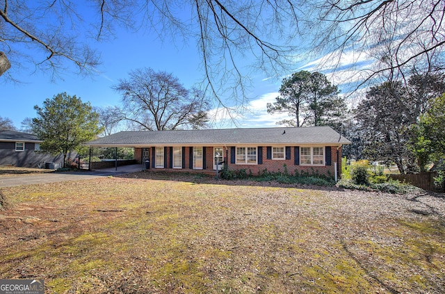 single story home featuring driveway, fence, a carport, and brick siding