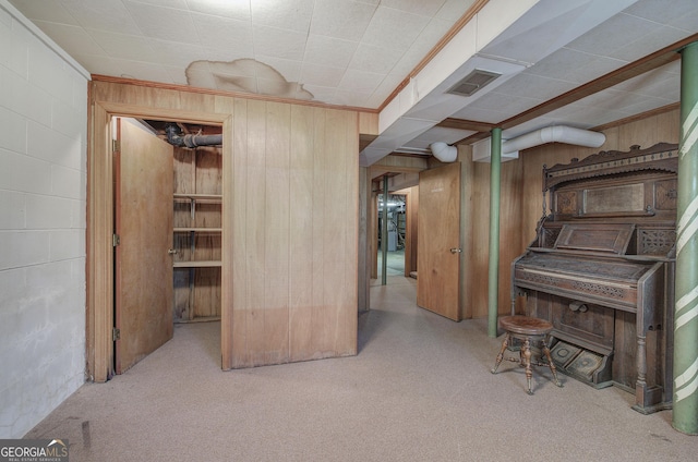 finished below grade area featuring crown molding, wooden walls, visible vents, and concrete block wall