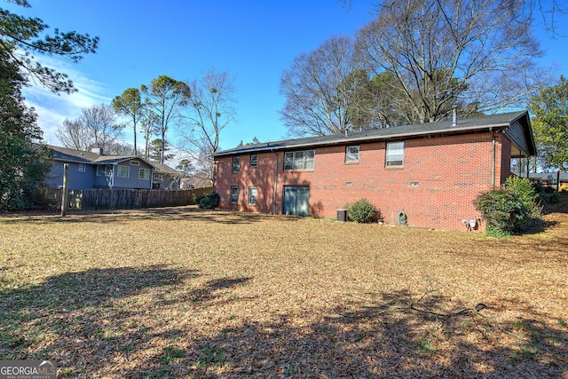 rear view of property featuring crawl space, brick siding, a yard, and fence