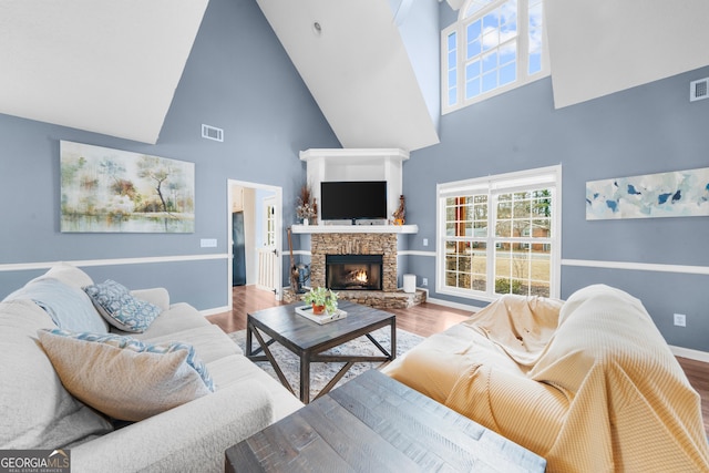 living room with a fireplace, wood finished floors, visible vents, and baseboards