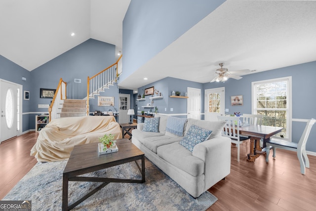 living room featuring recessed lighting, a ceiling fan, wood finished floors, high vaulted ceiling, and stairs