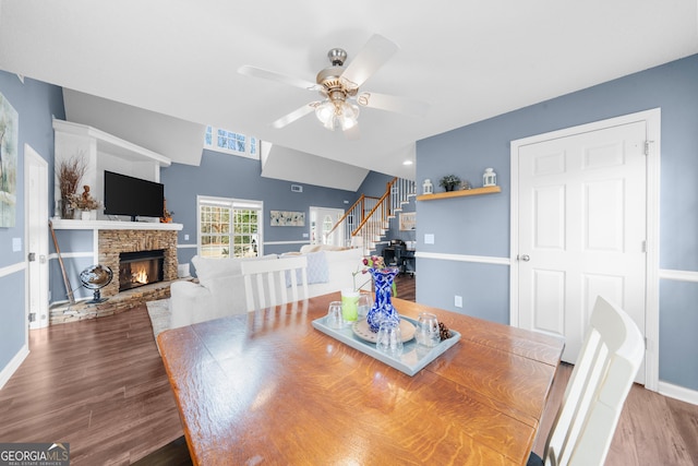 dining room featuring a fireplace, stairway, baseboards, and wood finished floors